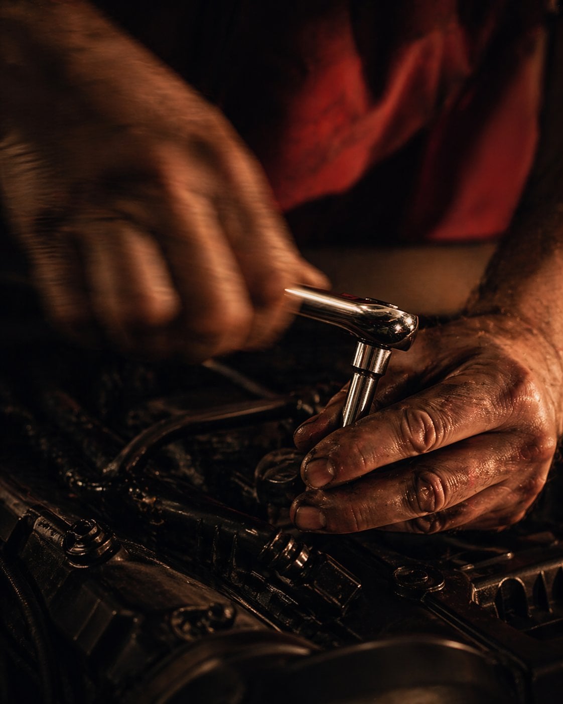 Hände eines Mechanikers arbeiten an einem Fahrzeug